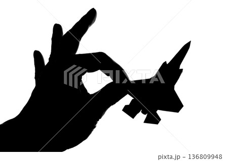 指でつままれたシルエットのジェット戦闘機 136809948