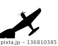 指でつままれたシルエットのプロペラ戦闘機 136810385