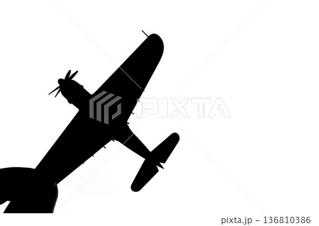 指でつままれたシルエットのプロペラ戦闘機 136810386