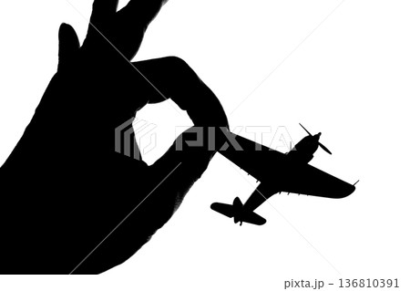 指でつままれたシルエットのプロペラ戦闘機 136810391