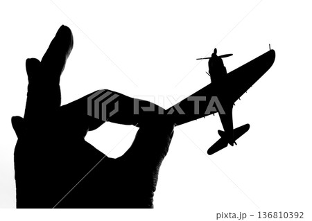 指でつままれたシルエットのプロペラ戦闘機 136810392