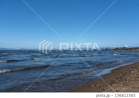 真冬の琵琶湖と遠く見える湖北の雪山の情景 136811565