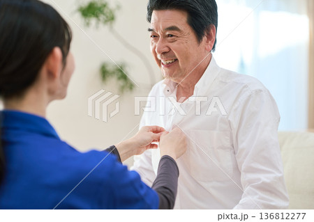 訪問介護でシャツのボタンを留めるアジア人介護士 訪問介護でシャツのボタンを留めるアジア人介護士 136812277