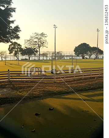 Coastal soccer field at sunset with calm water, illuminated by stadium lights Coastal soccer field at sunset with calm water, illuminated by stadium lights 136812453