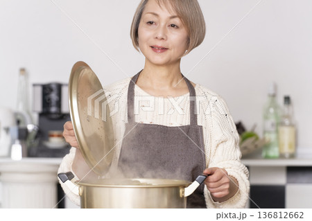 キッチンで豚汁を作りお椀に盛り付けるシニア女性 キッチンで豚汁を作りお椀に盛り付けるシニア女性 136812662