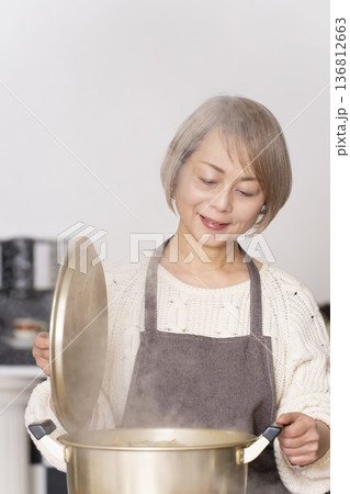キッチンで豚汁を作りお椀に盛り付けるシニア女性 136812663