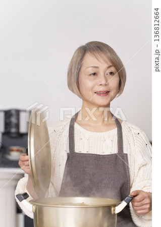 キッチンで豚汁を作りお椀に盛り付けるシニア女性 136812664