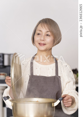 キッチンで豚汁を作りお椀に盛り付けるシニア女性 136812665