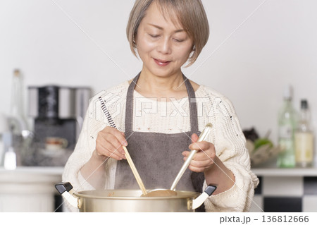 キッチンで豚汁を作りお椀に盛り付けるシニア女性 136812666