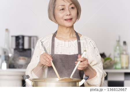 キッチンで豚汁を作りお椀に盛り付けるシニア女性 キッチンで豚汁を作りお椀に盛り付けるシニア女性 136812667