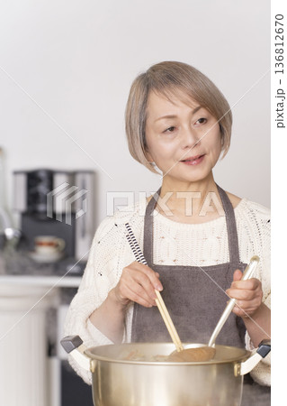 キッチンで豚汁を作りお椀に盛り付けるシニア女性 キッチンで豚汁を作りお椀に盛り付けるシニア女性 136812670