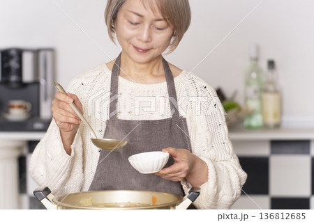 キッチンで豚汁を作りお椀に盛り付けるシニア女性 キッチンで豚汁を作りお椀に盛り付けるシニア女性 136812685