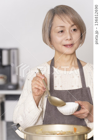 キッチンで豚汁を作りお椀に盛り付けるシニア女性 キッチンで豚汁を作りお椀に盛り付けるシニア女性 136812690