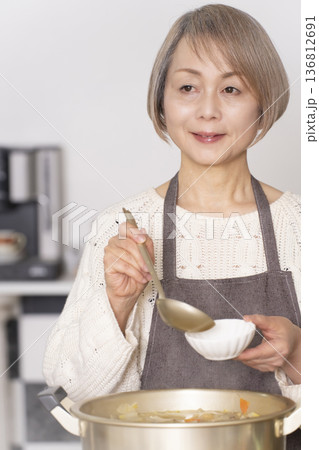 キッチンで豚汁を作りお椀に盛り付けるシニア女性 キッチンで豚汁を作りお椀に盛り付けるシニア女性 136812691
