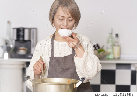 キッチンで豚汁を作りお椀に盛り付けるシニア女性 キッチンで豚汁を作りお椀に盛り付けるシニア女性 136812695