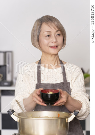 キッチンで豚汁を作りお椀に盛り付けるシニア女性 キッチンで豚汁を作りお椀に盛り付けるシニア女性 136812716