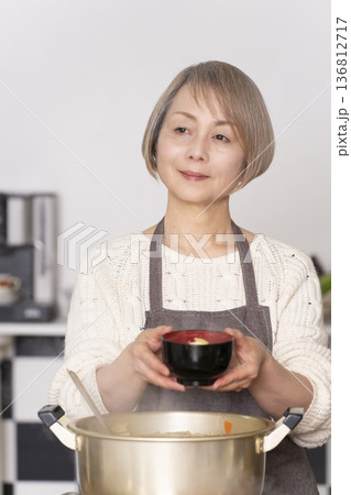 キッチンで豚汁を作りお椀に盛り付けるシニア女性 キッチンで豚汁を作りお椀に盛り付けるシニア女性 136812717