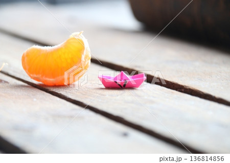 Slice of tangerine and paper and paper boat on vintage table. Summer time concept. 136814856
