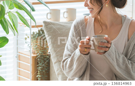 ソファーに座りホットドリンクを飲むおしゃれな女性 136814963