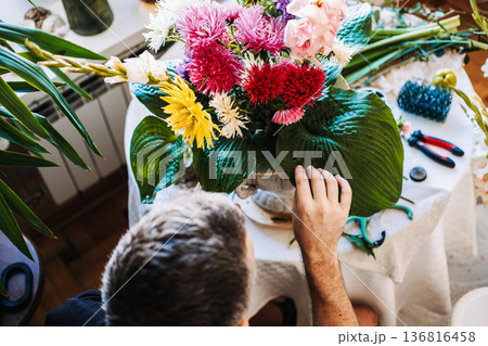 Hands of man adjust purple flower in large bouquet with dahlia and asters. Mental health hobbies, tactile healing, peaceful home environment, creative meditation, emotional wellness. Hands of man adjust purple flower in large bouquet with dahlia and asters. Mental health hobbies, tactile healing, peaceful home environment, creative meditation, emotional wellness. 136816458
