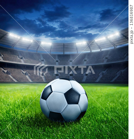 Ball on Silent football arena with glowing floodlights and vibrant grass surface 136816987