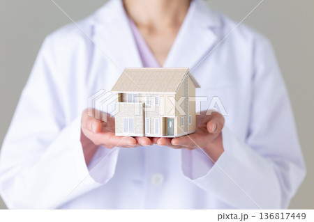 住宅模型を持つ白衣姿のミドル女性医師 136817449
