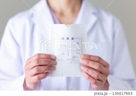 処方薬の袋を持つ白衣姿のミドル女性医師 処方薬の袋を持つ白衣姿のミドル女性医師 136817663