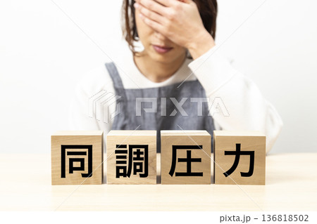 「同調圧力」と書かれたブロックとエプロン姿の女性 136818502