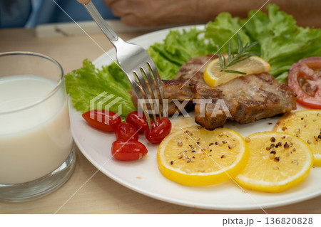 Asian elderly woman patient eating pork chop stake and vegetable salad for healthy food in hospital. Asian elderly woman patient eating pork chop stake and vegetable salad for healthy food in hospital. 136820828