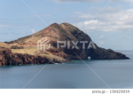 Ponta de Sao Lourenco volcanic slopes descend to smooth Atlantic water where a serene sea cave rests 136820834