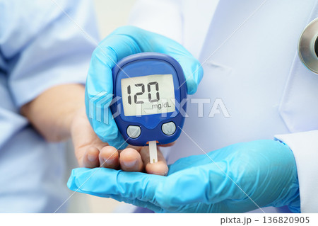 Asian doctor using digital glucose meter for check sample blood sugar level to treatment diabetes. 136820905