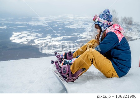 ゲレンデの頂上でスノーボードをする若い女性 136821906