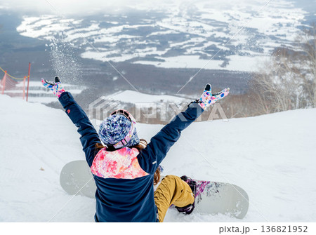 ゲレンデの頂上でスノーボードをする若い女性 136821952