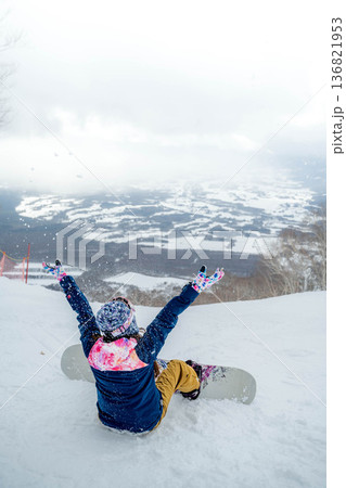 ゲレンデの頂上でスノーボードをする若い女性 136821953