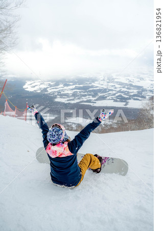 ゲレンデの頂上でスノーボードをする若い女性 136821954