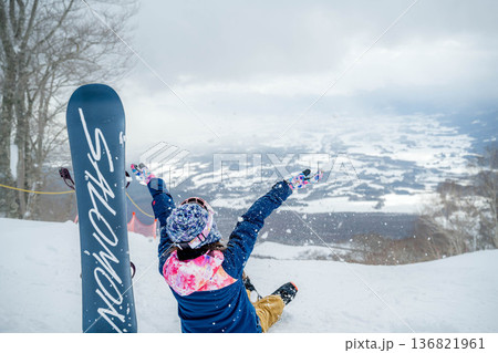 ゲレンデの頂上でスノーボードをする若い女性 136821961