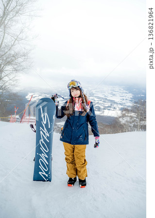 ゲレンデの頂上でスノーボードをする若い女性 136821964