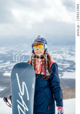 ゲレンデの頂上でスノーボードをする若い女性 136821968