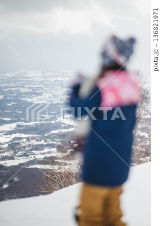 ゲレンデの頂上でスノーボードをする若い女性 136821971