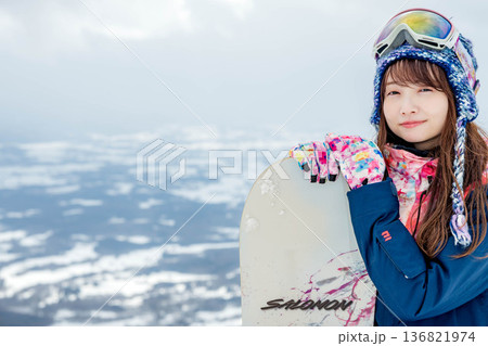 ゲレンデの頂上でスノーボードをする若い女性 136821974
