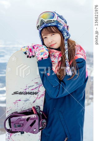 ゲレンデの頂上でスノーボードをする若い女性 136821976