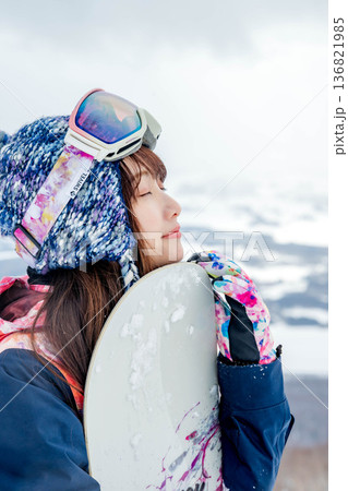 ゲレンデの頂上でスノーボードをする若い女性 136821985