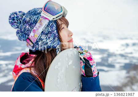 ゲレンデの頂上でスノーボードをする若い女性 136821987