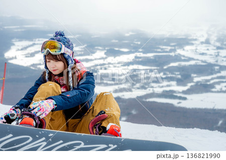 ゲレンデの頂上でスノーボードをする若い女性 136821990