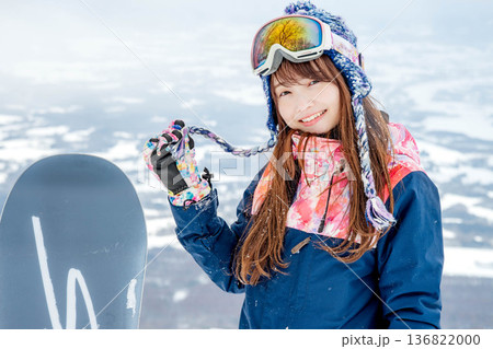 ゲレンデの頂上でスノーボードをする若い女性 ゲレンデの頂上でスノーボードをする若い女性 136822000
