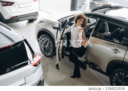 Far top view. Pretty woman is in the car retail shop 136822016