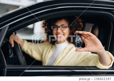 In glasses, with keys in hand. Happy woman is sitting in the car 136822147