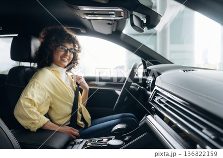 Fastens the seat belt. Happy woman is sitting in the car Fastens the seat belt. Happy woman is sitting in the car 136822159