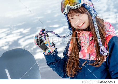 ゲレンデの頂上でスノーボードを楽しむ若い女性 136822254