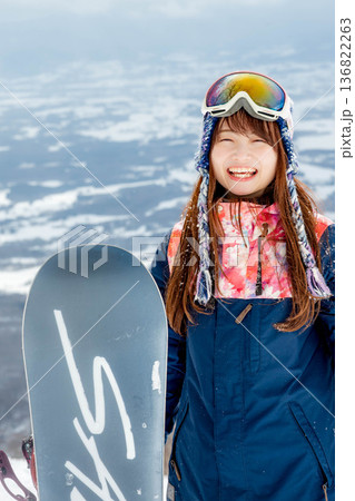 ゲレンデの頂上でスノーボードを楽しむ若い女性 136822263